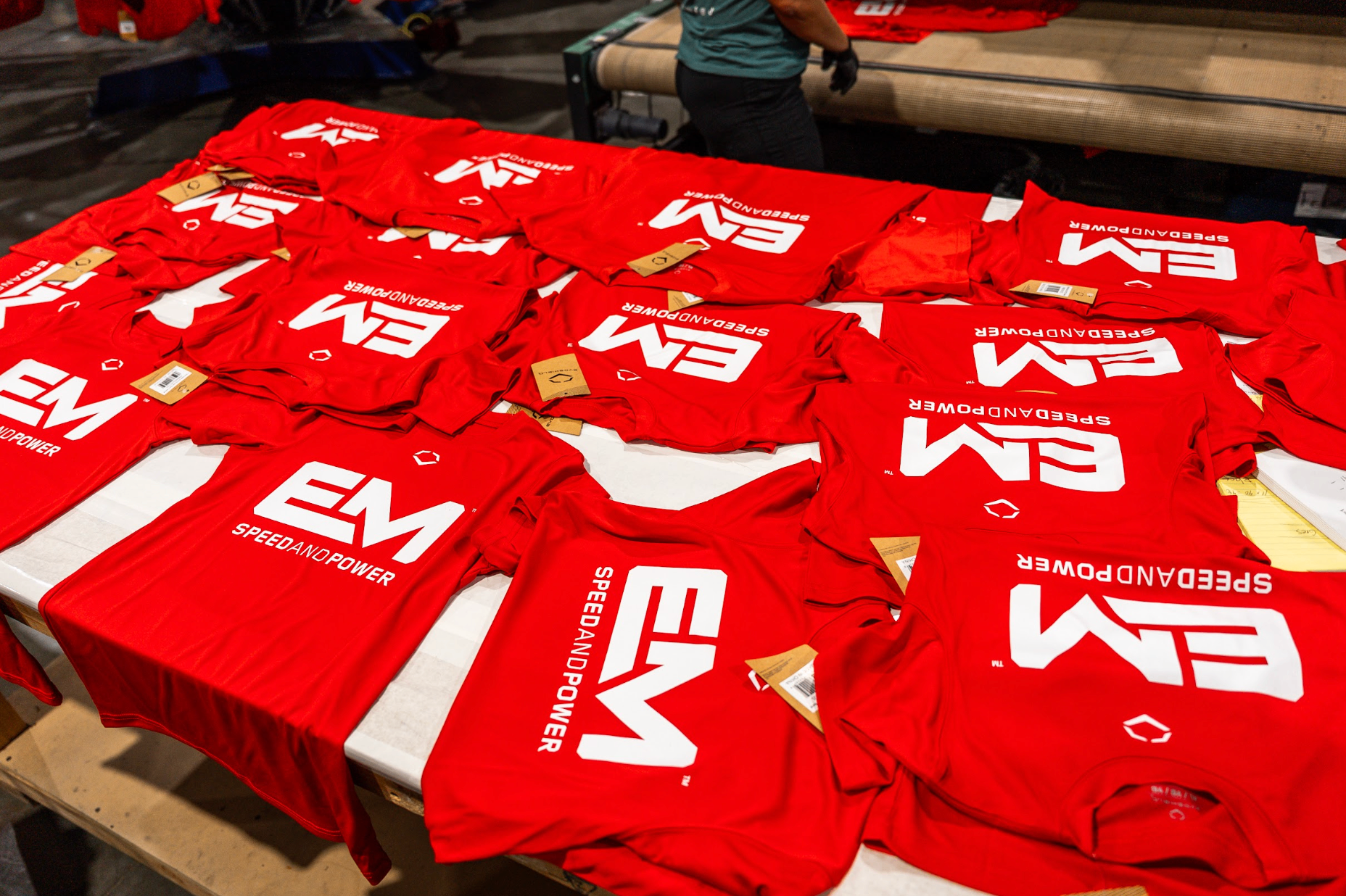 Large batch of EM Speed and Power red shirts laid out after a commercial screen printing run in Las Vegas