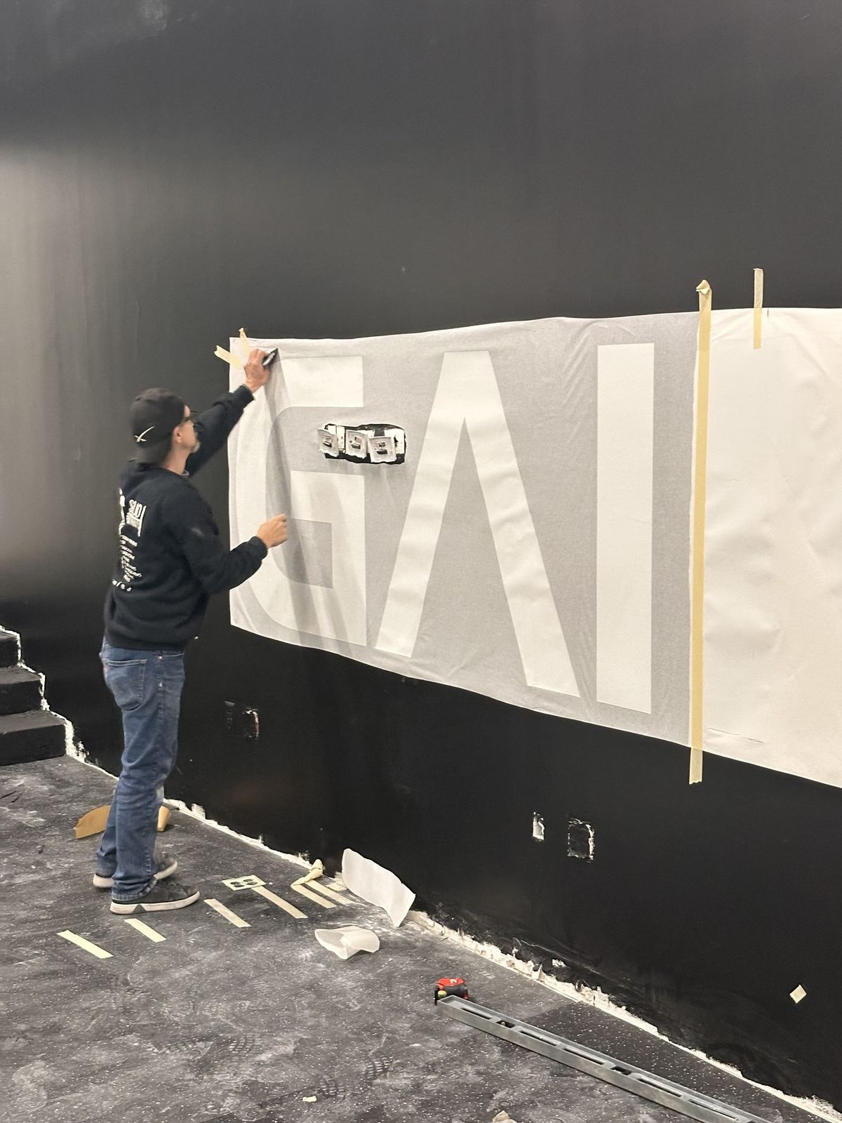 Large-format wall stencil / mural install - masking and alignment on black wall