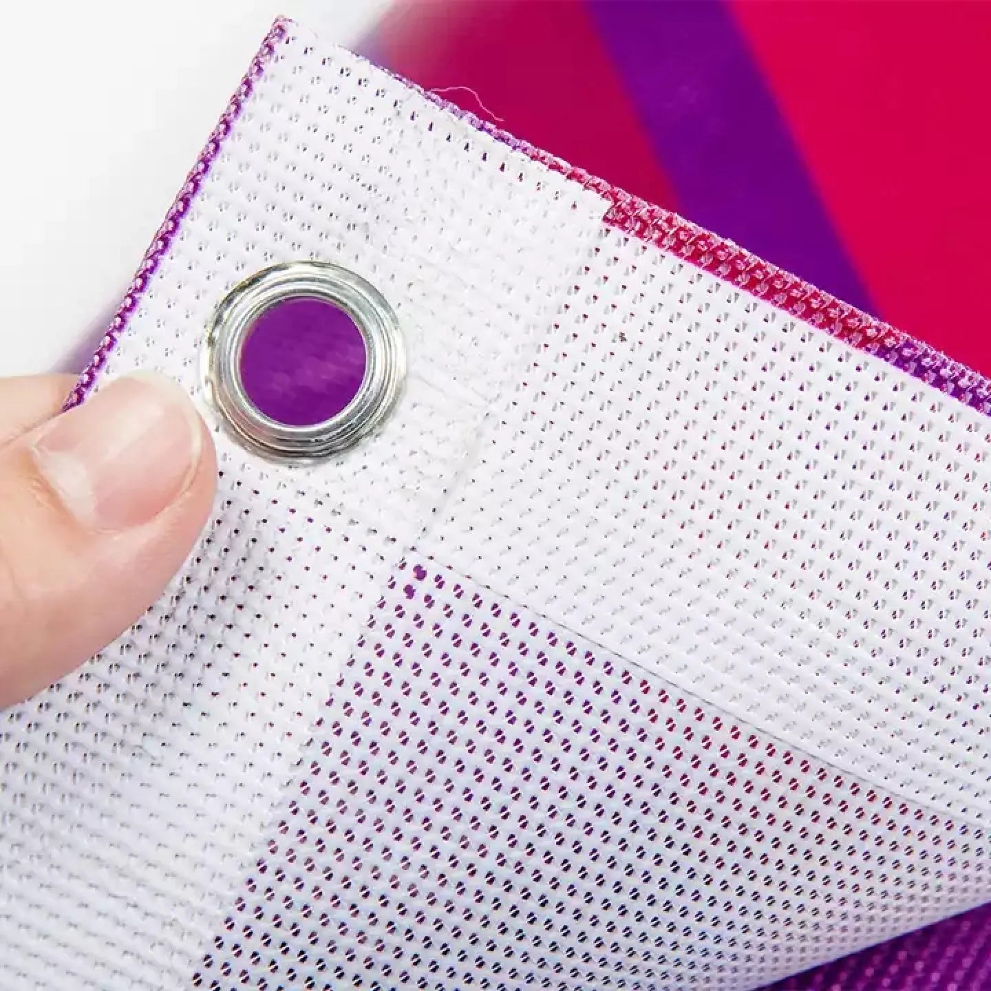 Close-up of a mesh banner corner showing the perforated weave and metal grommet