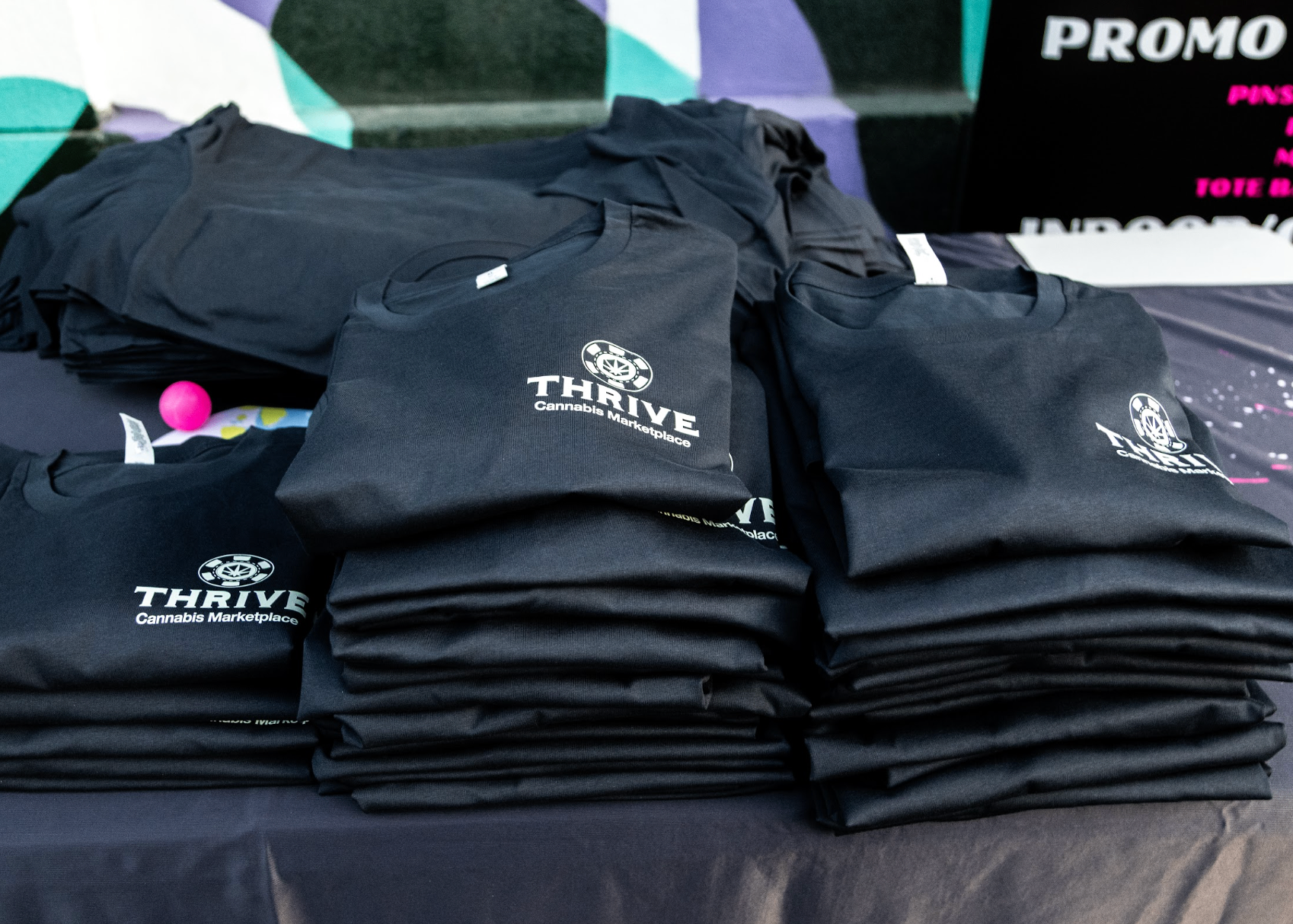 Folded Thrive Cannabis Marketplace shirts stacked after screen printing in the Las Vegas shop