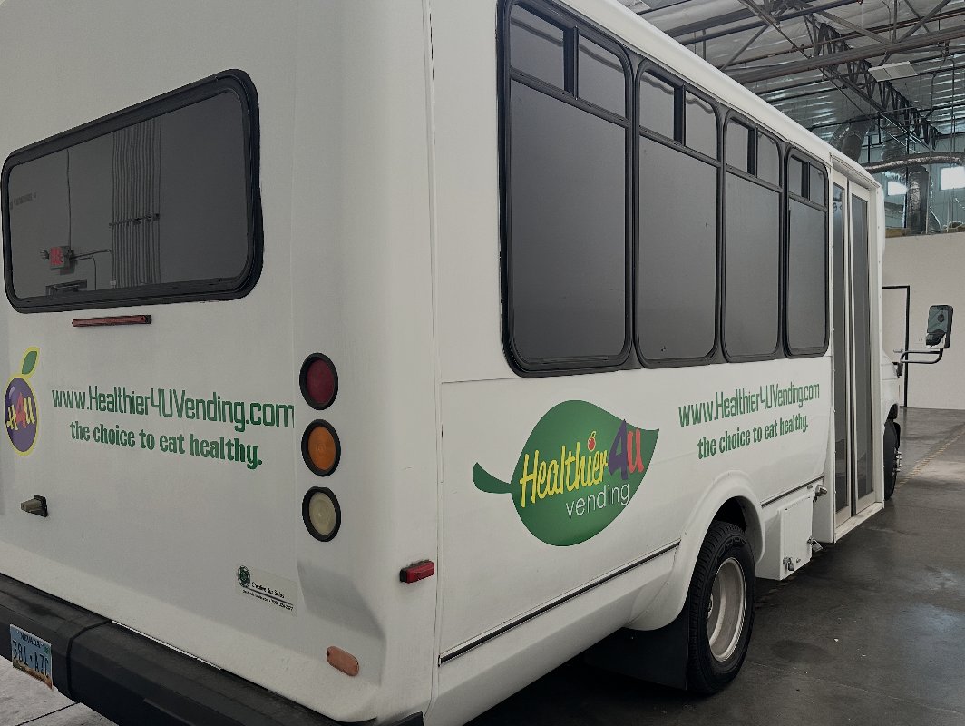 Shuttle bus partial wrap — rear and side branding with web + tagline