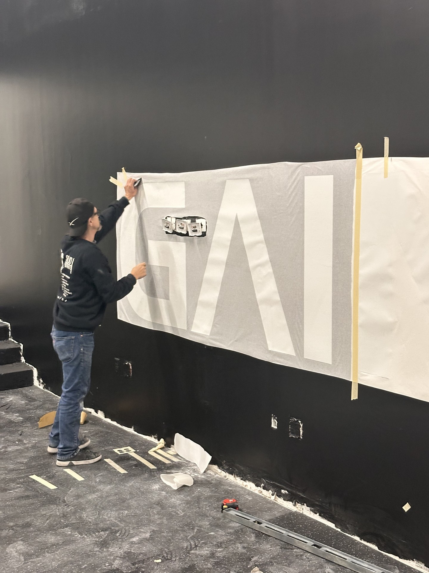 Large-format wall stencil / mural install — masking and alignment on black wall